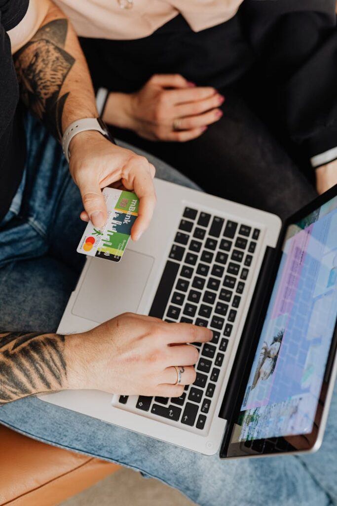 A Man Using a Laptop while Holding a Bank Card